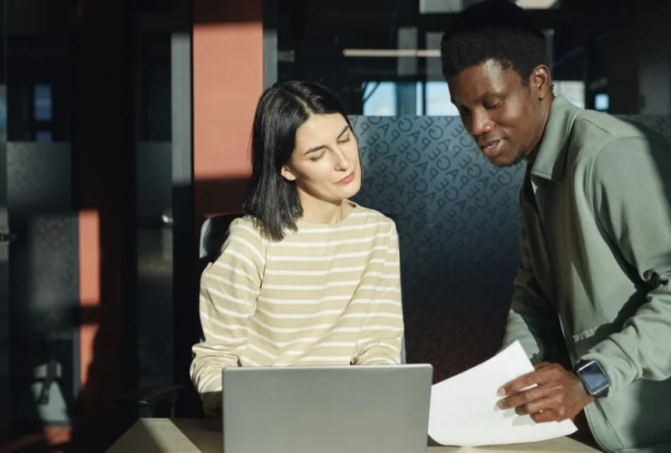 Two professionals collaborating at laptop in modern office, representing executive assistance services for growing companies.