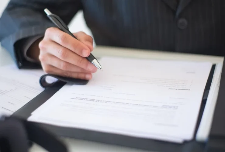 Professional signing documents, demonstrating executive assistant backup coverage and business process procedures.