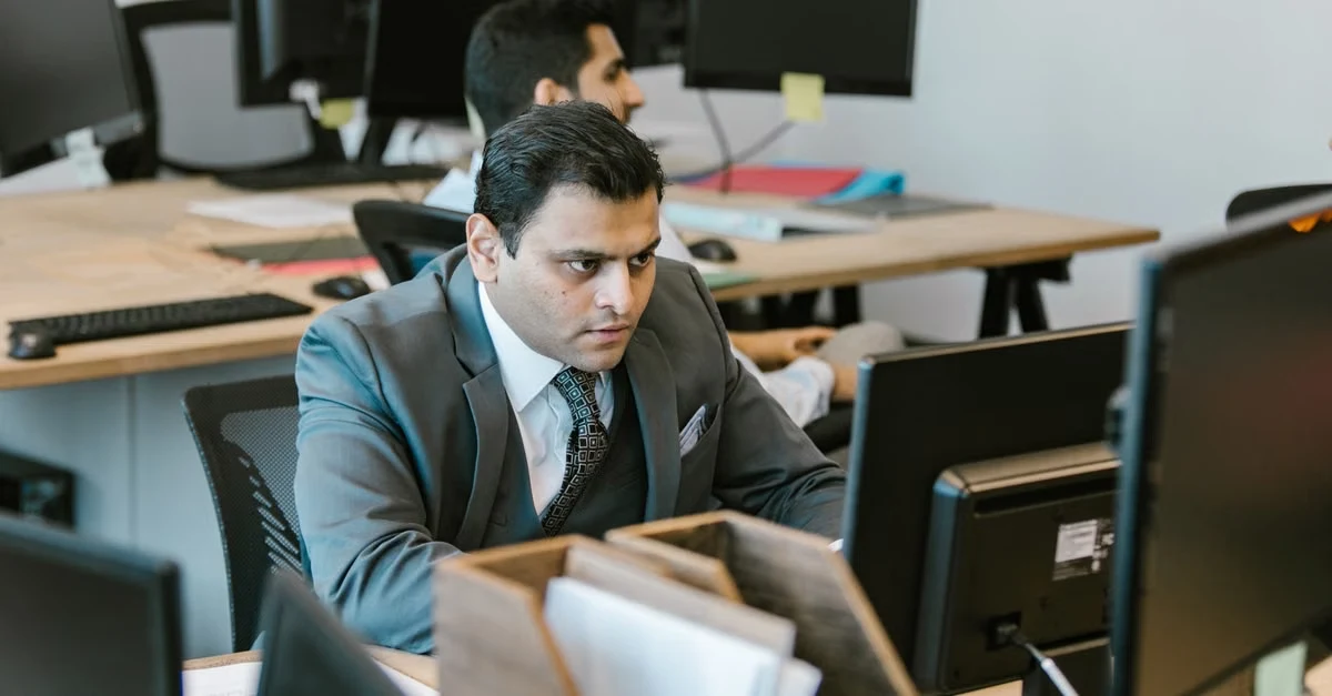 Executive assistant professional boundaries demonstrated through focused businessman at desk in modern office environment.