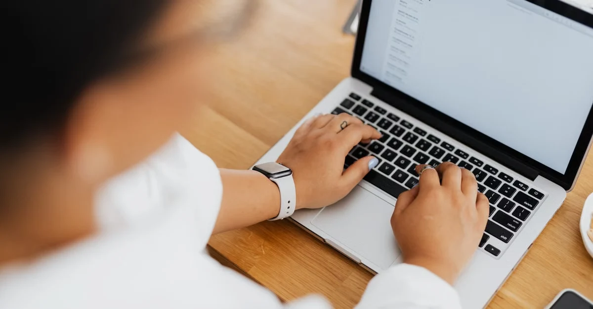 Executive assistant typing follow-up email on laptop after keynote support event.