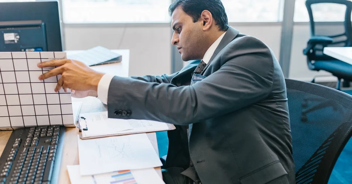 Executive assistant sales leader reviewing financial charts and data analytics at office desk.