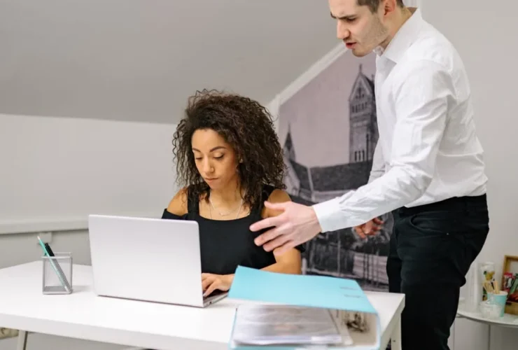 Two professionals collaborating at desk with laptop, exploring zirtual alternative solutions for remote team management.