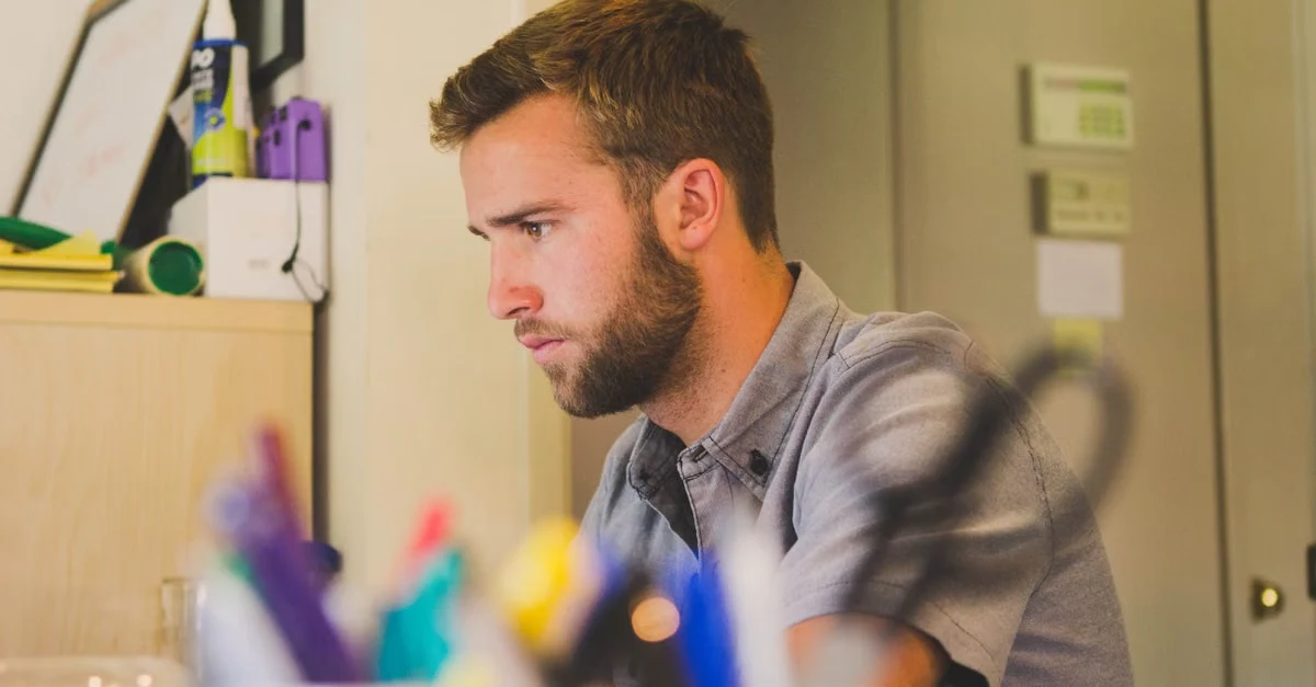 Executive assistant founder focused at desk with colorful office supplies and equipment in background.