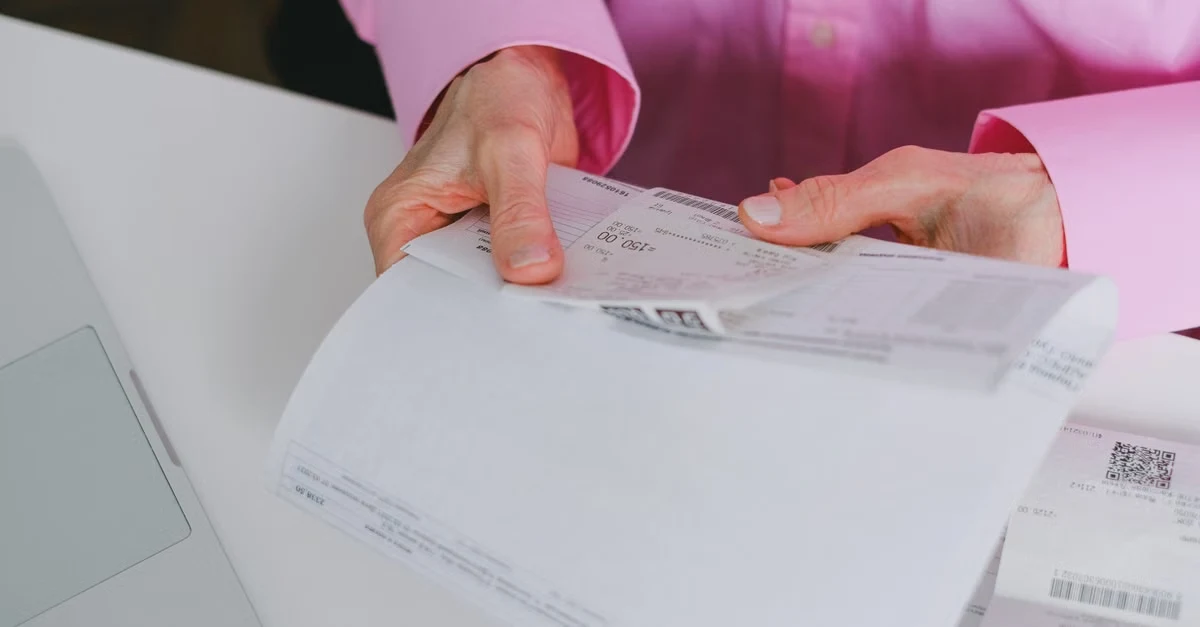 Person in pink shirt reviewing corporate card expense audit documents on white desk.