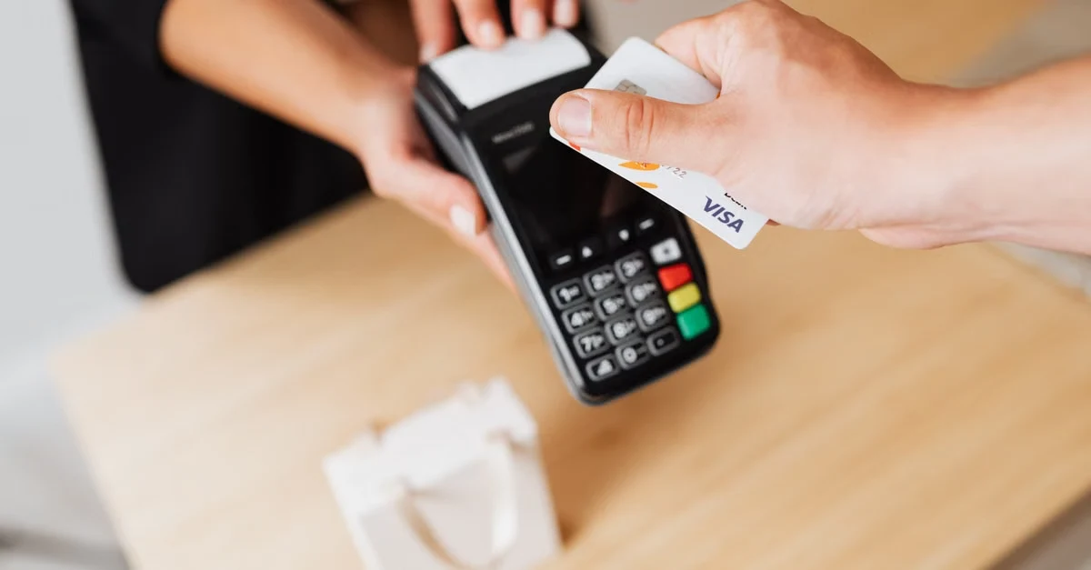 Customer using corporate card with payment terminal for contactless transaction processing.